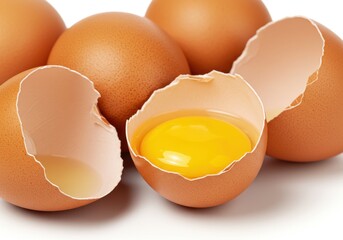 Close up of cracked brown chicken eggs revealing yellow yolk inside surrounded by whole eggshells