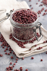 Glass jar full of azuki beans on gray closeup. Dried uncooked legumes. Vegetarian protein