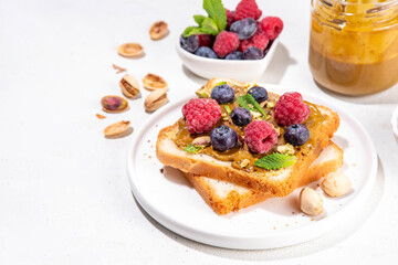 Pistachio paste toast. Summer breakfast delicious sandwiches with pistachio butter spread, with fresh berries. Balanced healthy vitamins and macronutrients snack