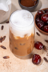 Healthy organic date seed coffee, iced coffee latte cup, made with grated date seeds, with whole date fruits and seeds on beige background . Alternative coffee hot drink