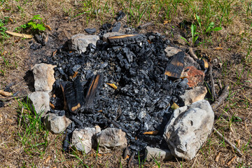 Fire pit remnants in a grassy area after a gathering on a sunny day