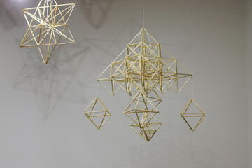 Artistic geometric mobile made of wooden sticks suspended in a minimalistic space showcasing...