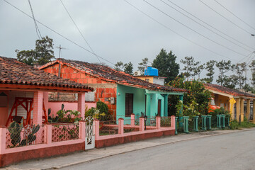 A row of charming, pastel-colored colonial houses in Viñales, Cuba, showcasing traditional architectural elements such as tiled roofs, wooden shutters, and classical columns. cuba