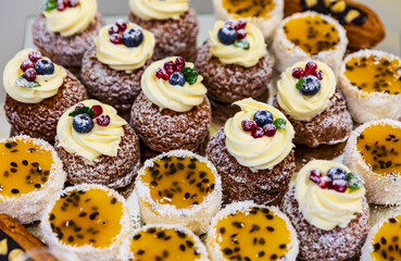 A tempting display of miniature pastries adorned with cream, berries, and tropical passion fruit.