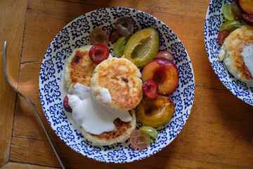 Syrniki with cream and plum. Top view