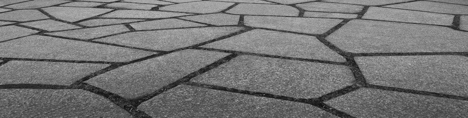 Fototapeta premium abstract splinters background of a lined with granite tiles pavement. Texture of a granite stones pavement lined with geometric figures small grey gray beige granite slabs. floor flooring backdrop.
