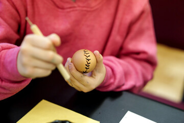 Woman hands painting Easter eggs with black bee wax, traditional Lithuanian method
