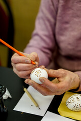 Woman hands painting Easter eggs with black bee wax, traditional Lithuanian method