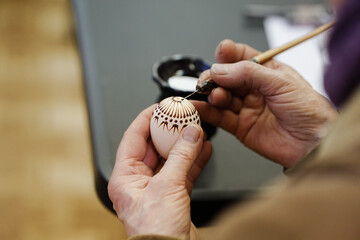 Woman hands painting Easter eggs with black bee wax, traditional Lithuanian method
