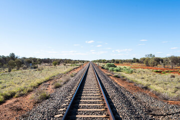Fototapeta premium Empty railway along the Adelaide–Darwin rail corridor in a remote part of the Australian Outback. The railway is used by The Ghan rail service