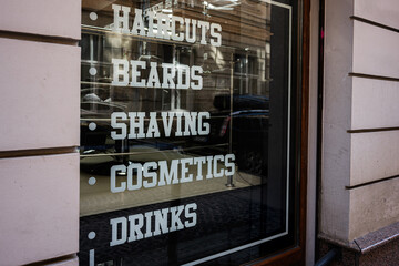 Barber shop window display showcasing services like haircuts, cosmetics, and drinks