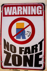 Humorous metal sign warning no fart zone with bold text and graphic
