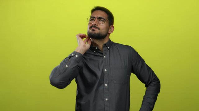 Young man wearing glasses scratching head in thoughtful pose isolated on yellow background