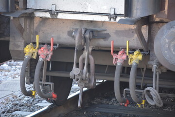 Detailed view of train couplings and hoses in a railway yard during daylight