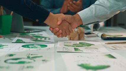 Fototapeta premium A close-up of hands shaking over business strategy documents featuring graphs and charts, symbolizing collaboration and agreement in a professional setting. SACTR