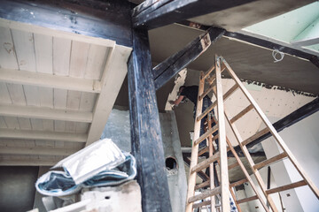 Male builder at work overalls plastering and restoring old wall using a construction trowel.