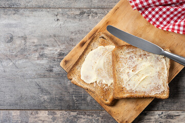 Sliced fresh bread and butter on wooden table. Top view. Copy space