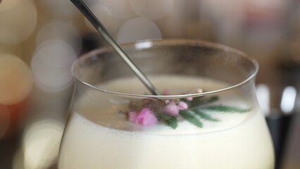 Closeup mixed passion fruit and sweet liquor cocktail decorated adding pink flower on top, making special creative drink menu list for advertisement in focusing alcohol refreshing showcase. Vinosity.