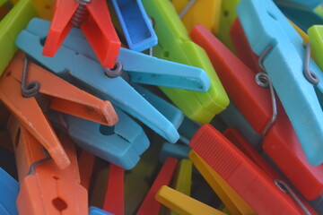 Colorful clothespins in a messy pile on a bright background during daylight