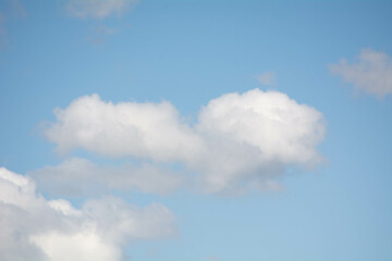 Soft white clouds drift across a clear blue sky during a sunny afternoon
