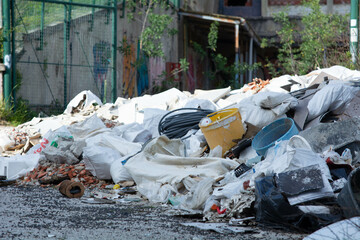 Pile of discarded construction materials and waste near abandoned building in urban area