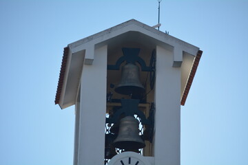 Two large bells hanging in a tower against a clear blue sky during the afternoon