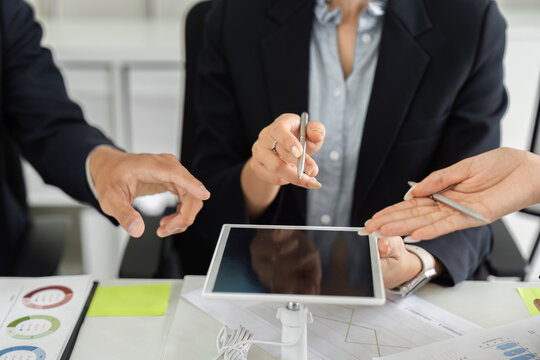 Collaboration and Digital Tools. Team members exchanging ideas using a tablet during a strategy meeting.