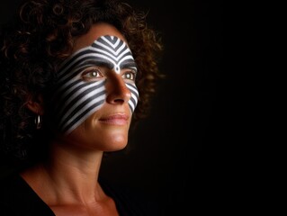 Woman wearing abstract striped face paint and curly hair under directional lighting evoking conceptual themes of contrast identity and surrealism