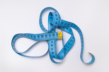Measuring tape, centimeter on gray background, top view flat lay. Concept of an accessory for measuring body volumes, fitness, sport. Tool for dressmaker and sewing