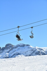 Ski resort view by winter with ski lift skiers on the slopes