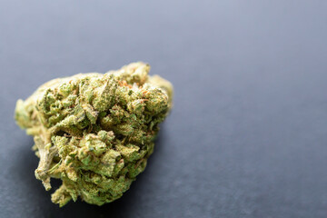 Macro shot of cannabis bud on dark background showing detailed texture, trichomes and natural...