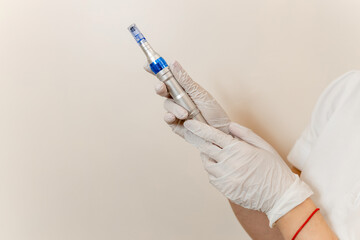 Device for microneedling procedure with dermapen, tip with needles, held in hands of cosmetologist