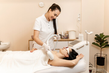 Obraz premium laser hair removal, hair removal procedure, girl lying on sofa in beauty salon, arm and armpit hair removal, spa and cosmetology concept