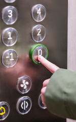Hand pressing ground floor button in modern elevator interior panel. © Kufotos