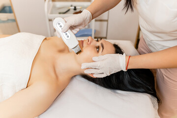 The soothing vibrations from the ultrasonic facial massager create a rejuvenating experience as a professional skincare professional cleanses and revitalizes the client's radiant 