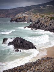 Waves crashing on the rugged rocky coast of Praia do Abano, Portugal