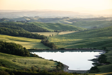 Beautiful landscape of Tuscany with a lake and rolling green hills at sunset - Tuscany Italy.