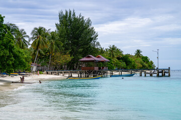 View of a tropical beach village with a wooden pier stretching into turquoise waters