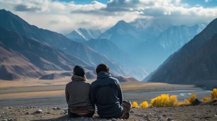 Back view of anonymous couple of tourists admiring majestic mountains under shiny sky in sunlight
