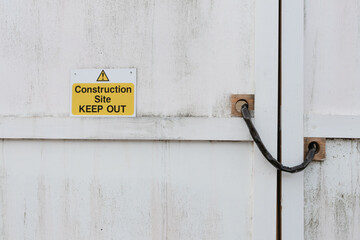 Construction Site Keep Out warning sign with symbol in yellow and black on white wooden gate panel