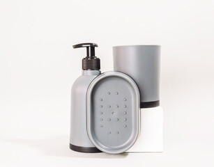 Set of bathroom accessories including a soap dispenser, a soap dish, and a cup