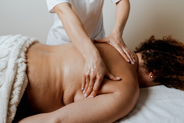 Obese middle-aged woman receives a special body massage intended for weight reduction and correction of bad posture. Modern weight loss physical therapy and beauty spa concept.