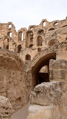 Fototapeta premium Stone structures in the arena of the ancient Roman amphitheater at El Djem, Tunisia, with walls with open arches rising above
