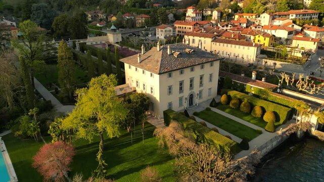 slow motion drone footage of Villa Balbiano Lake Como, Italy. historic courtyard, lush gardens, elegant architecture, lake and mountains view. luxury, travel, architecture, destination wedding sunset 