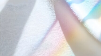 Abstract iridescent light refracting through sheer white fabric creates colorful rainbow patterns.