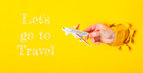 Hand holding a toy airplane with the words Let's go to travel
