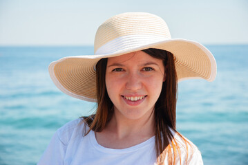 Woman enjoying a sunny day at the beach in wide-brimmed hat. Happy summer days, travel and vacation...