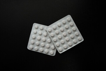 Two medicine packages in front of black background. 50 pills
