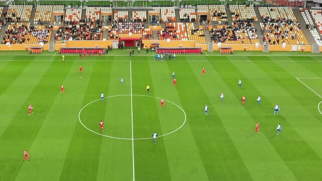 Football match with teams teams dressed in red and blue are engaged in a thrilling football match at a vibrant stadium. Fans cheer enthusiastically as players strategically maneuver for a goal