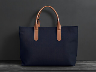 Stylish navy tote bag with brown leather handles displayed against a dark backdrop